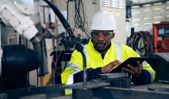 African American factory worker working with adept robotic arm